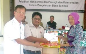 Asian Agri's Head of Sustainability and CSR Welly Pardede hands out a waste management guidebook to a trash bank management trainee